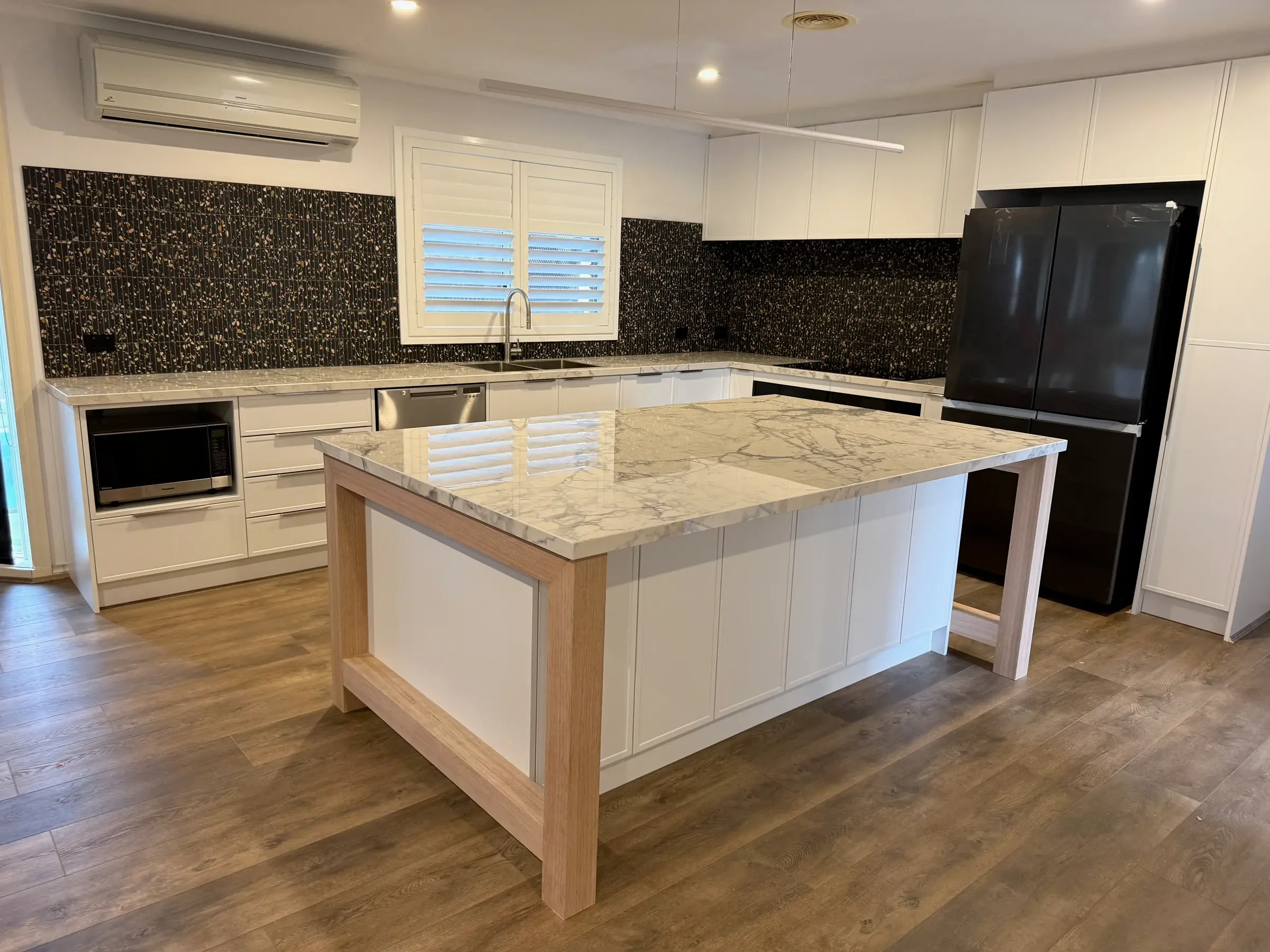 Completed Bluestone kitchen with white cabinetry and a timber-framed island