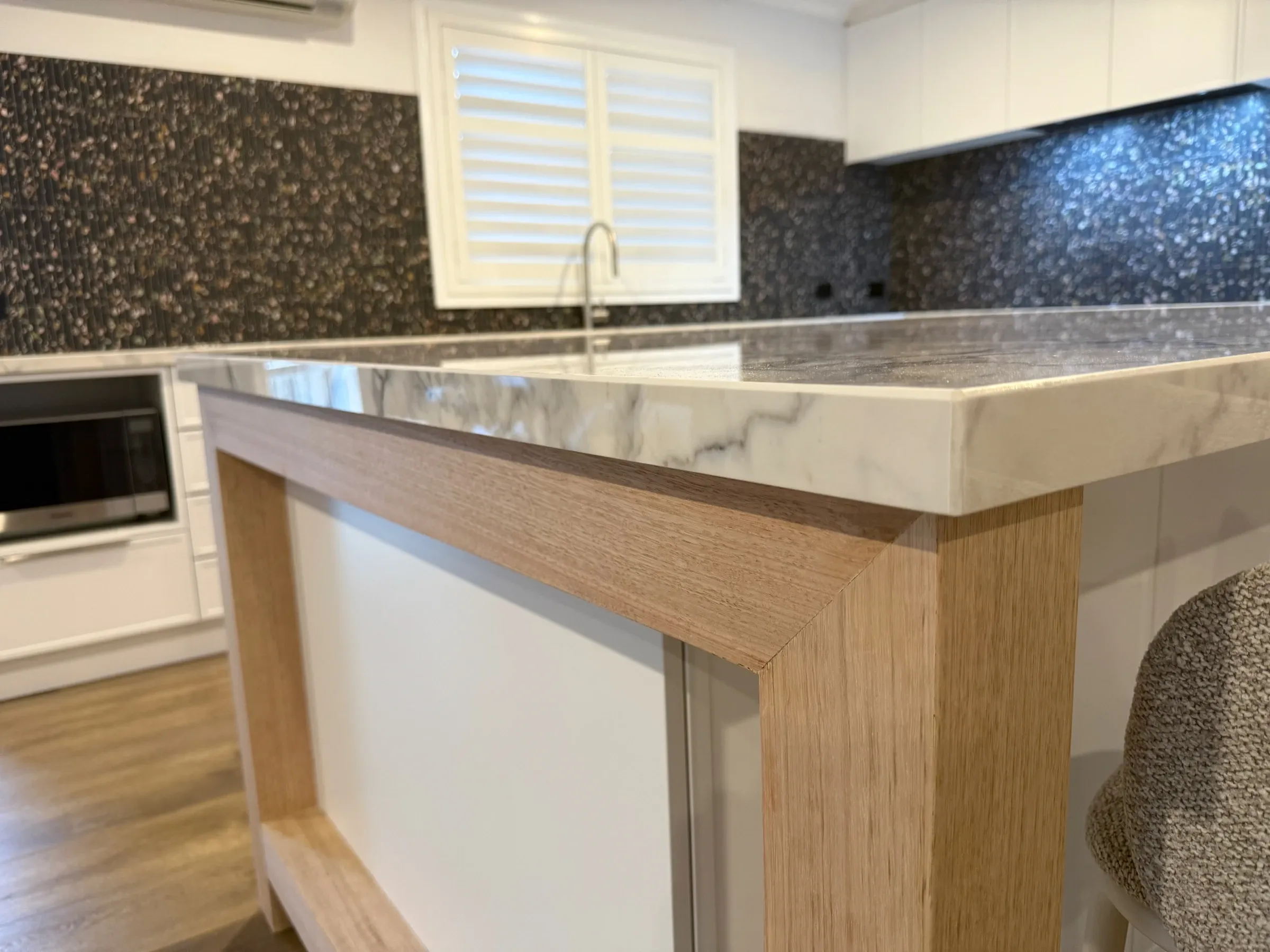 Stone benchtop and timber island frame in the completed Bluestone kitchen