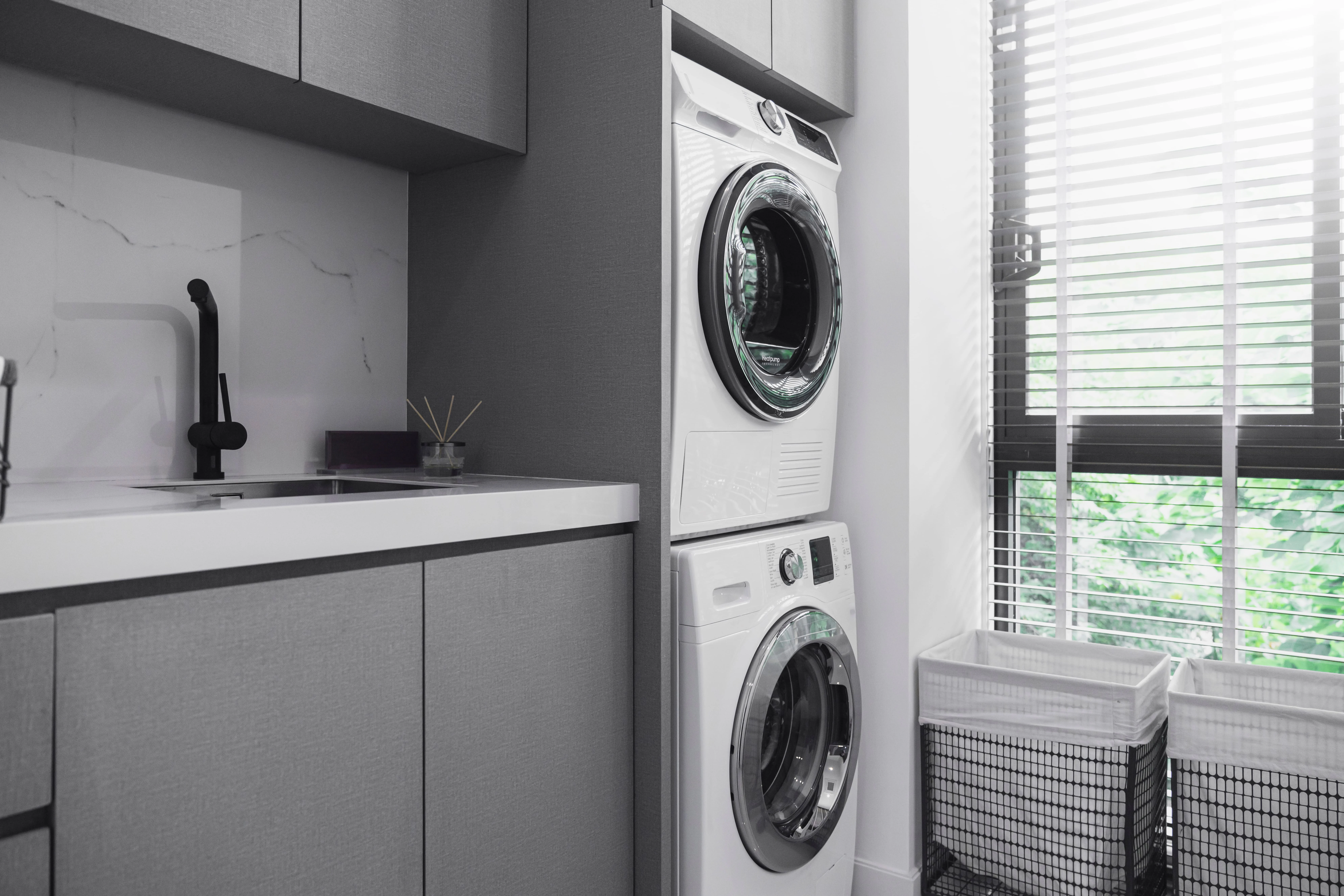B-Spoke laundry with grey cabinetry, stacked appliances, a black tap and window blinds