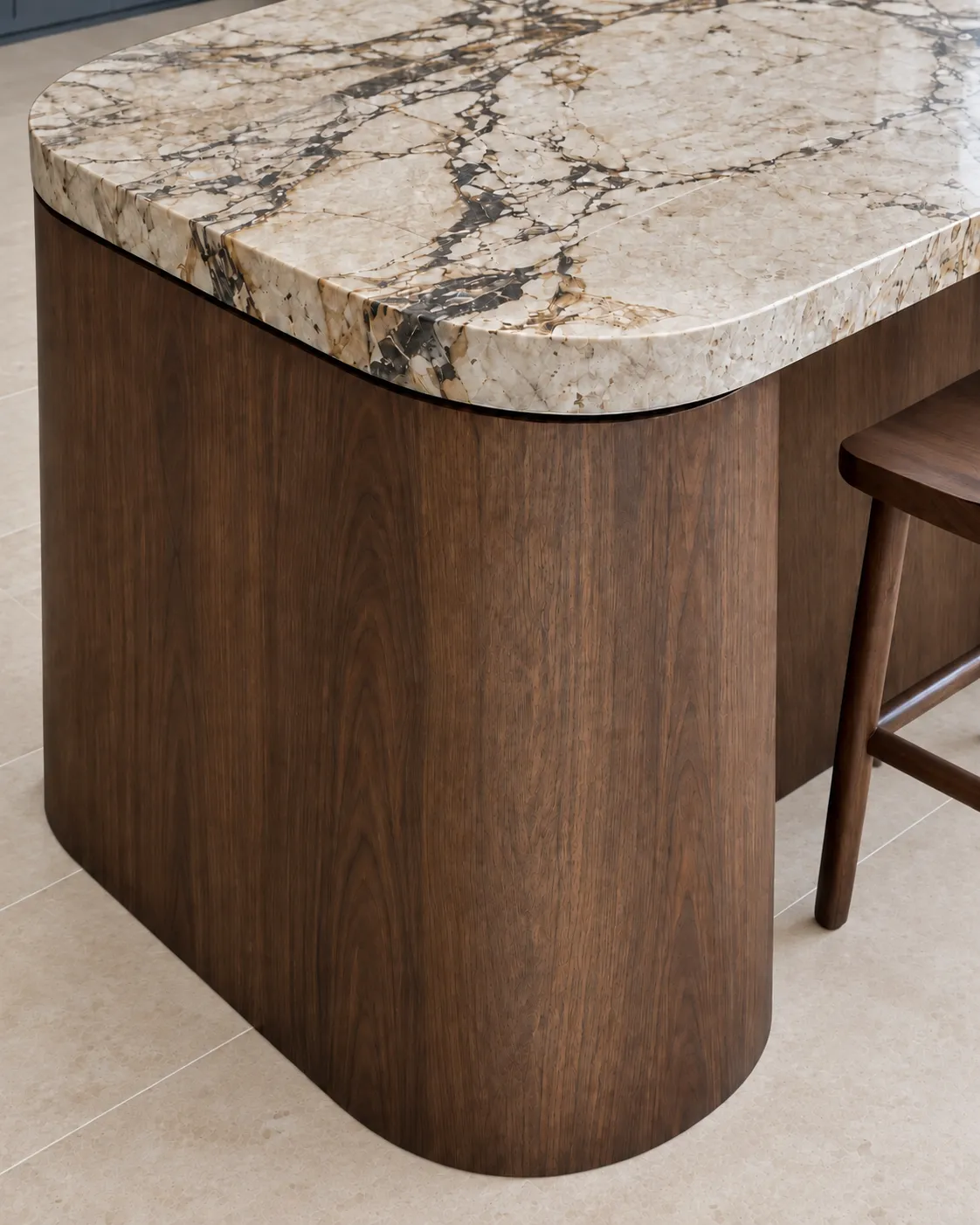Close detail of the curved dark-oak island end and cream stone benchtop with dark veining